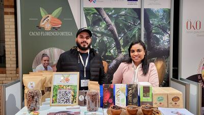 Two people stand behind booth displaying Dominican chocolate