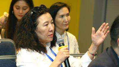 Woman speaks into microphone with hand raised