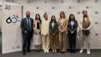 students from The Geneva Graduate Institute (IHEID) and ITC staff pose with sign for ITC's 60th anniversary