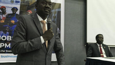 South Sudanese government official speaks into a microphone in conference venue