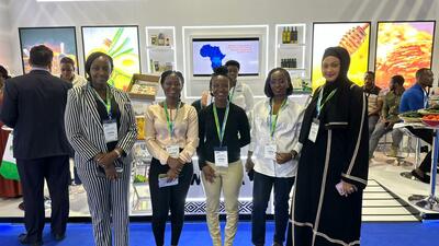 Group of five women standing in front of a Rwanda country trade fair booth section. 